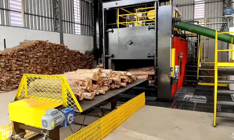 Forno industrial secando toras de eucalipto em esteira.