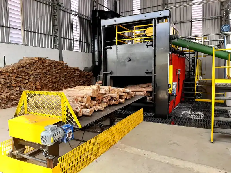 Forno industrial secando toras de eucalipto em esteira.
